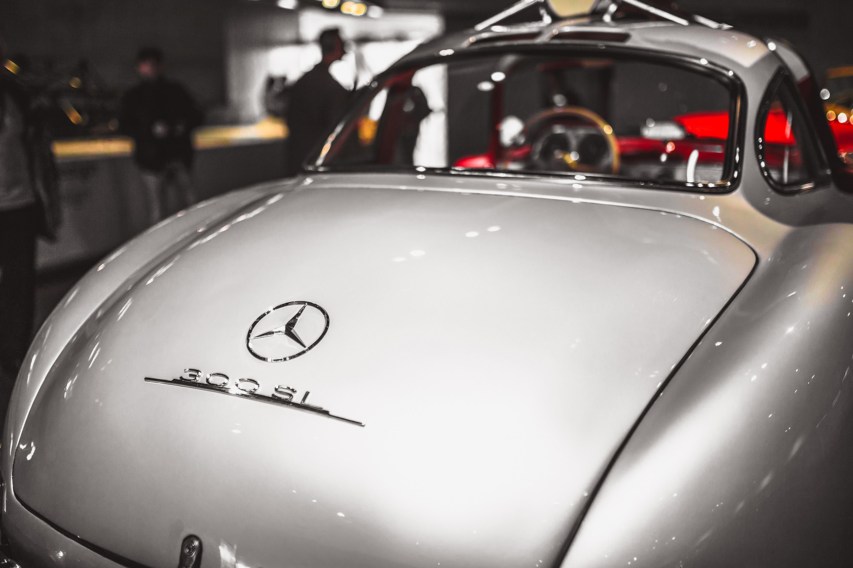 Heckansicht eines silbernen Mercedes-Benz 300 SL mit geöffneter Flügeltür in Ausstellung.