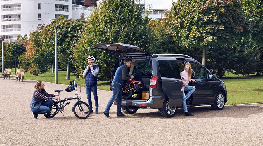 Familie bereitet Fahrradtour vor und lädt Bikes aus einem geöffneten Ford Tourneo – Freizeit und Flexibilität perfekt kombiniert.