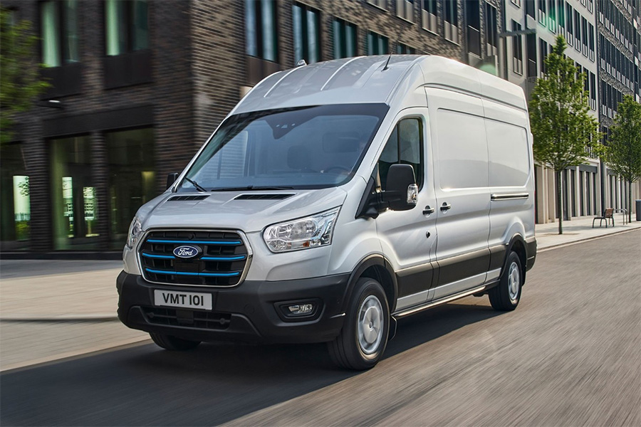 Ford Transit Elektro-Transporter fährt durch eine moderne Stadtstraße – kraftvoll, leise und emissionsfrei. Ideal für gewerblichen Einsatz im urbanen Raum.