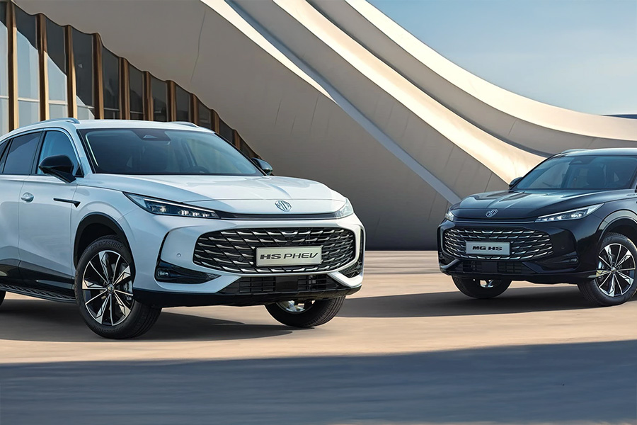 Zwei MG-SUVs – einer weiß, einer schwarz – stehen nebeneinander vor einem modernen, geschwungenen Gebäude mit großen Fensterflächen.
