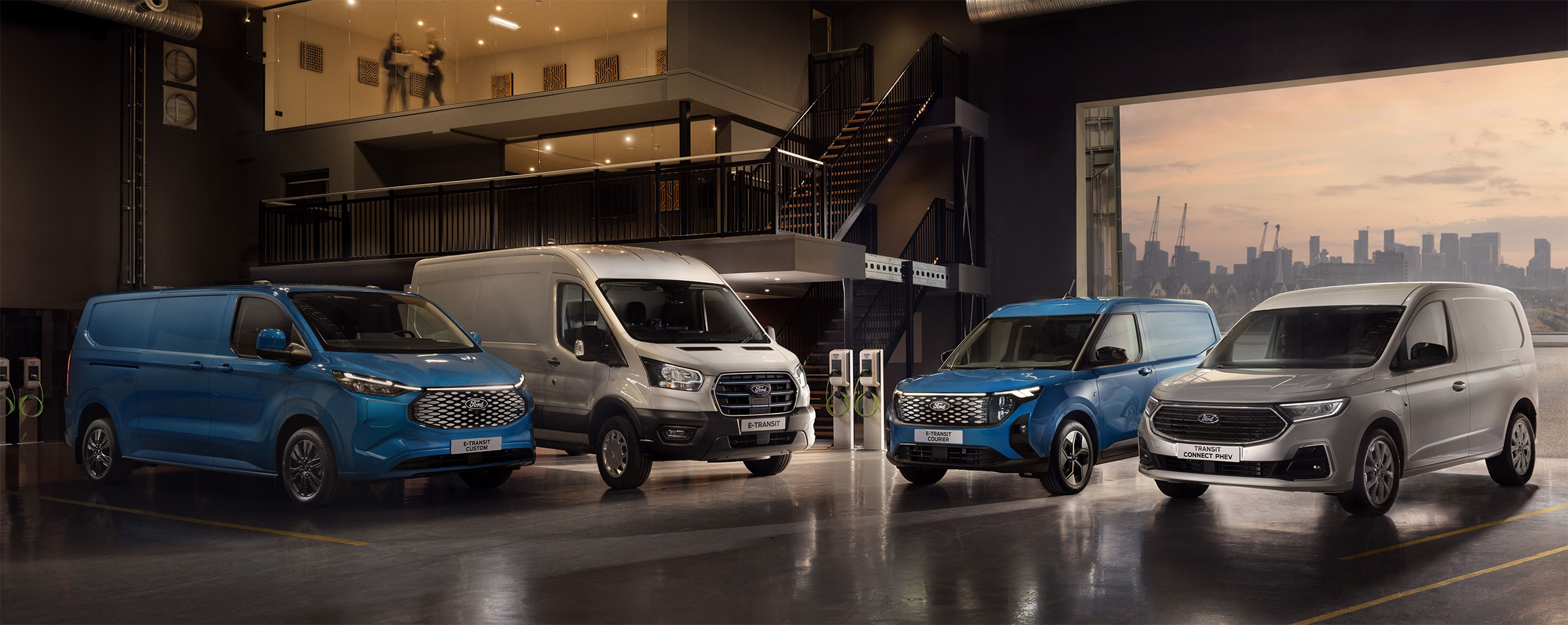 4 verschiedene Ford Modelle nebeneinander in einer Lagerhalle, abwechselnd lackiert in Blau oder Grau.