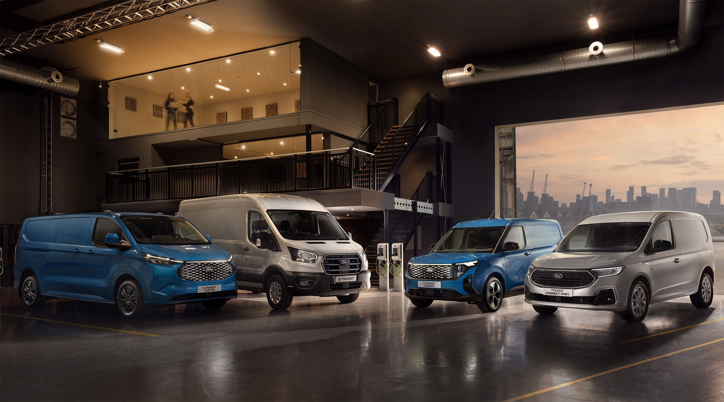 4 verschiedene Ford Modelle nebeneinander in einer Lagerhalle, abwechselnd lackiert in Blau oder Grau.