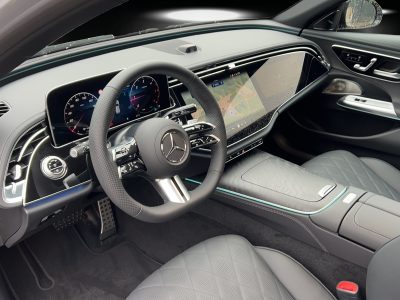Innenraum eines Mercedes-Benz mit volldigitalem Widescreen-Cockpit, Multifunktionslenkrad, Ambientebeleuchtung und hochwertiger Lederausstattung in Rautensteppung – moderne, luxuriöse Atmosphäre.